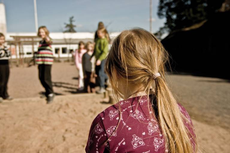 Kuvituskuva tytöstä joka jäänyt leikin ulkopuolelle koulun pihalla